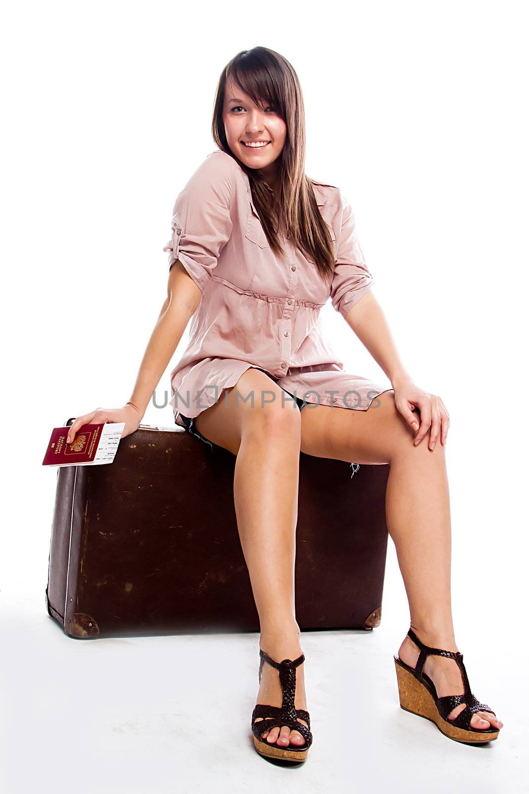 Photo of a young and beautiful girl with a suitcase, passport and ticket isolated on white background