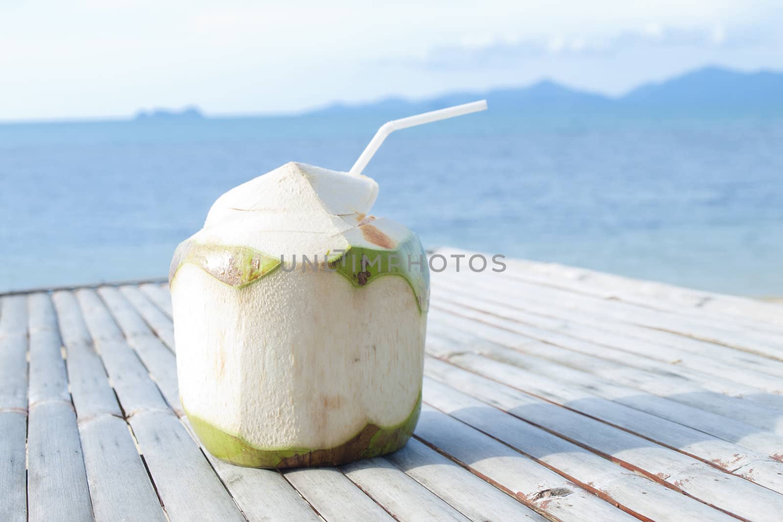 Coconut Water Drink on bamboo table with sea background by jakgree