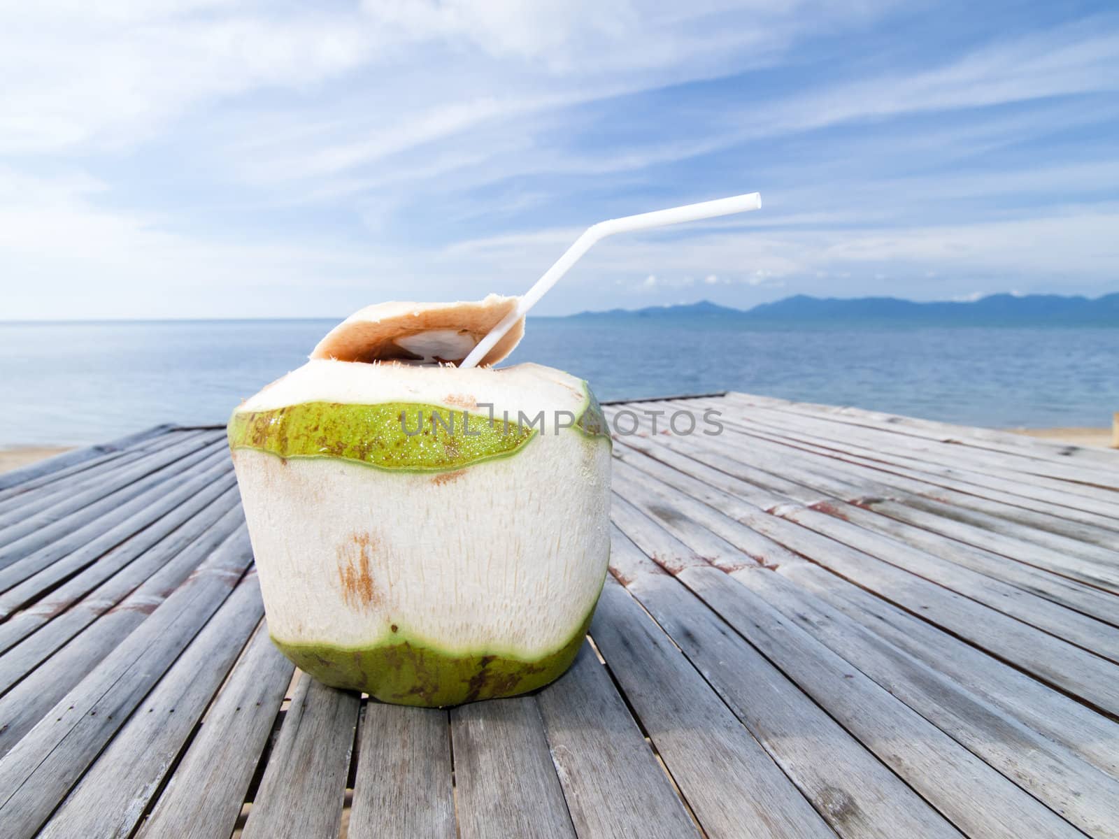 Coconut Water Drink on bamboo table with sea background by jakgree