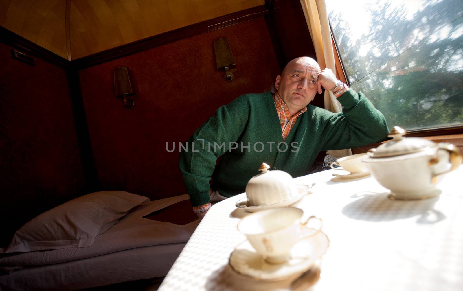 Adult man sitting in sleeping wagon in train, looking through the window