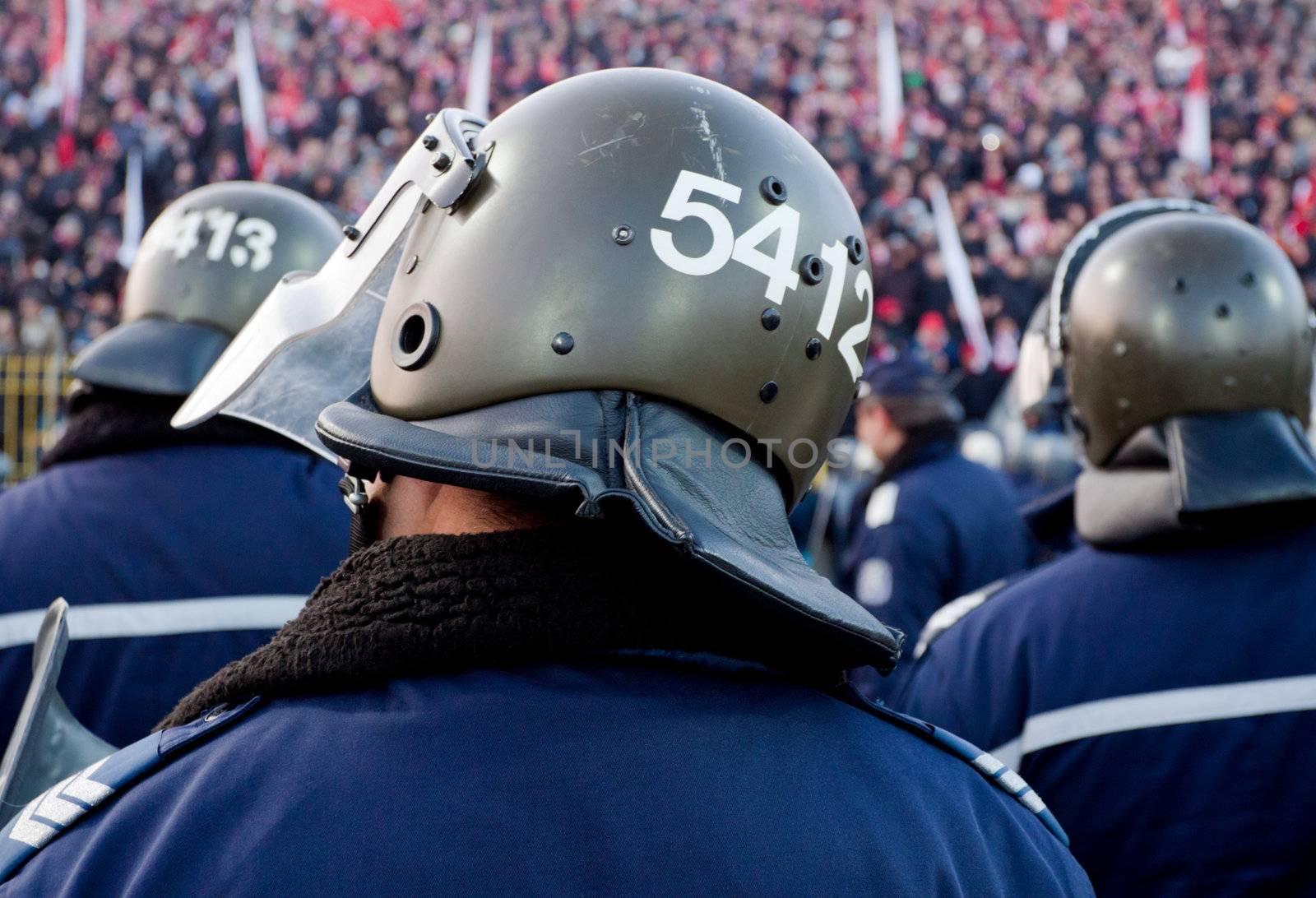 Backs of policemen guarding at stadium during a football game