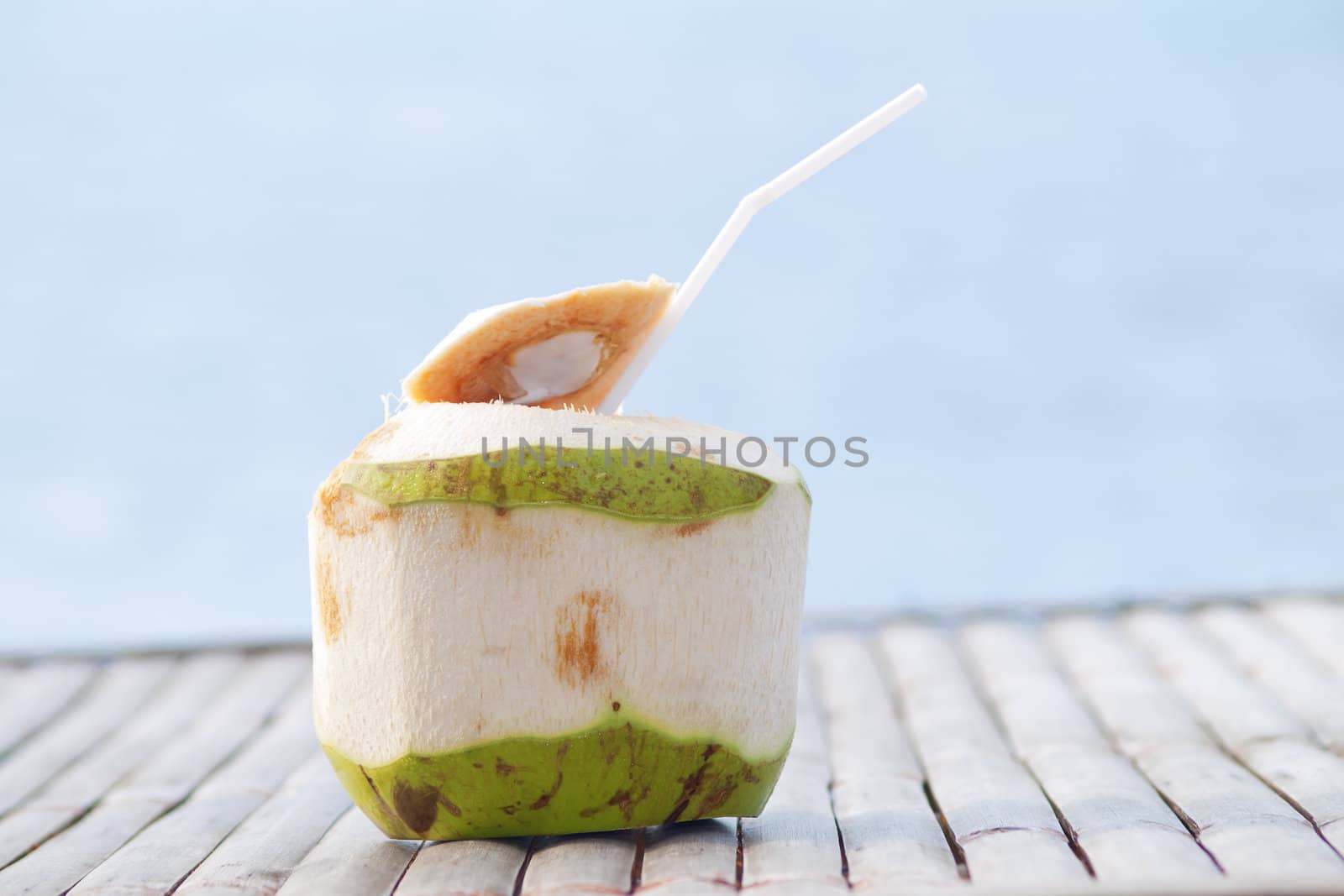 Coconut Water Drink on bamboo table with sea background