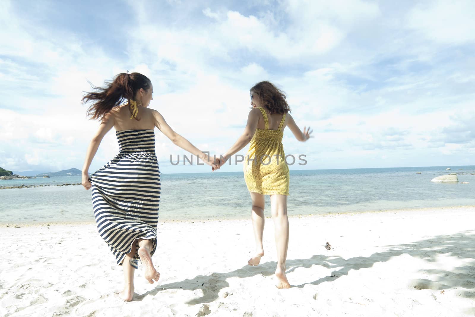 woman running together sand by sea edge on blue sky background by jakgree