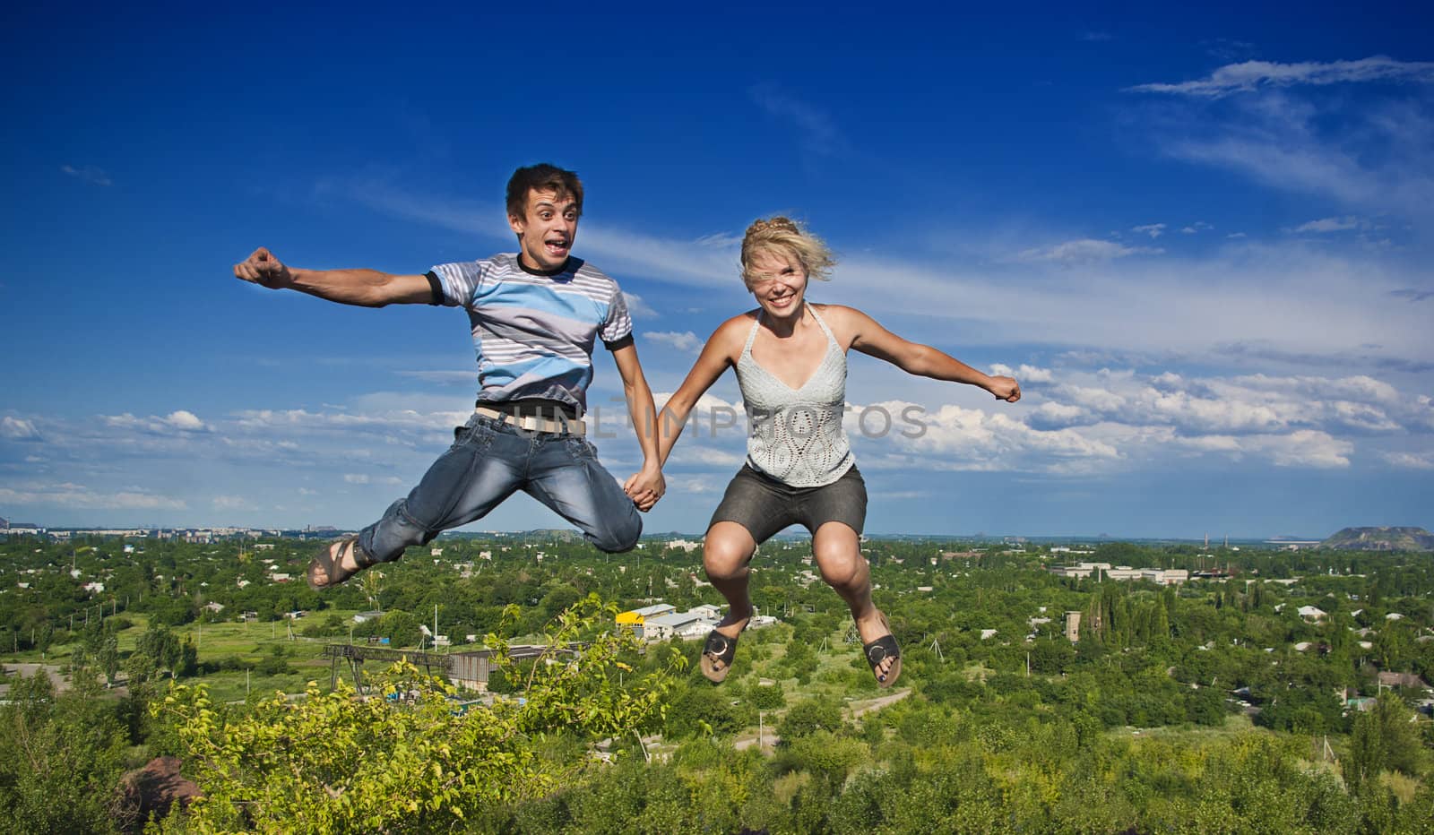 Boy and girl jumping against a background of beautiful sky
