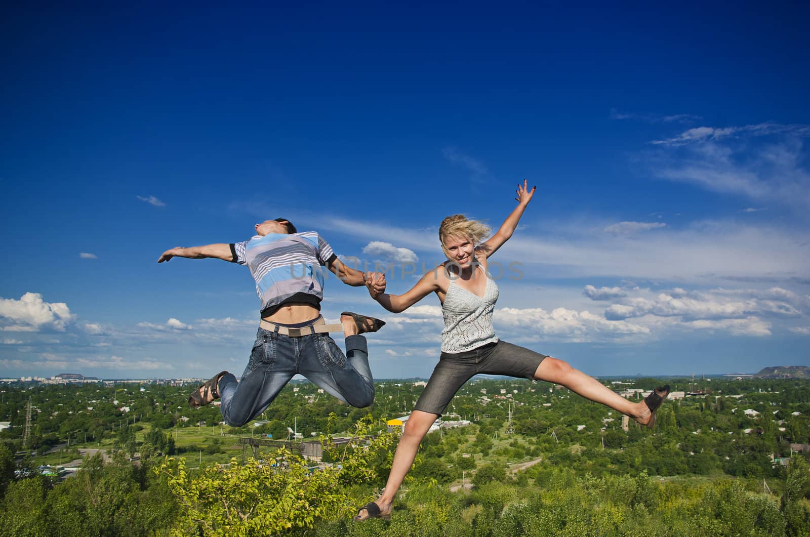 Boy and girl jumping against a background of beautiful sky