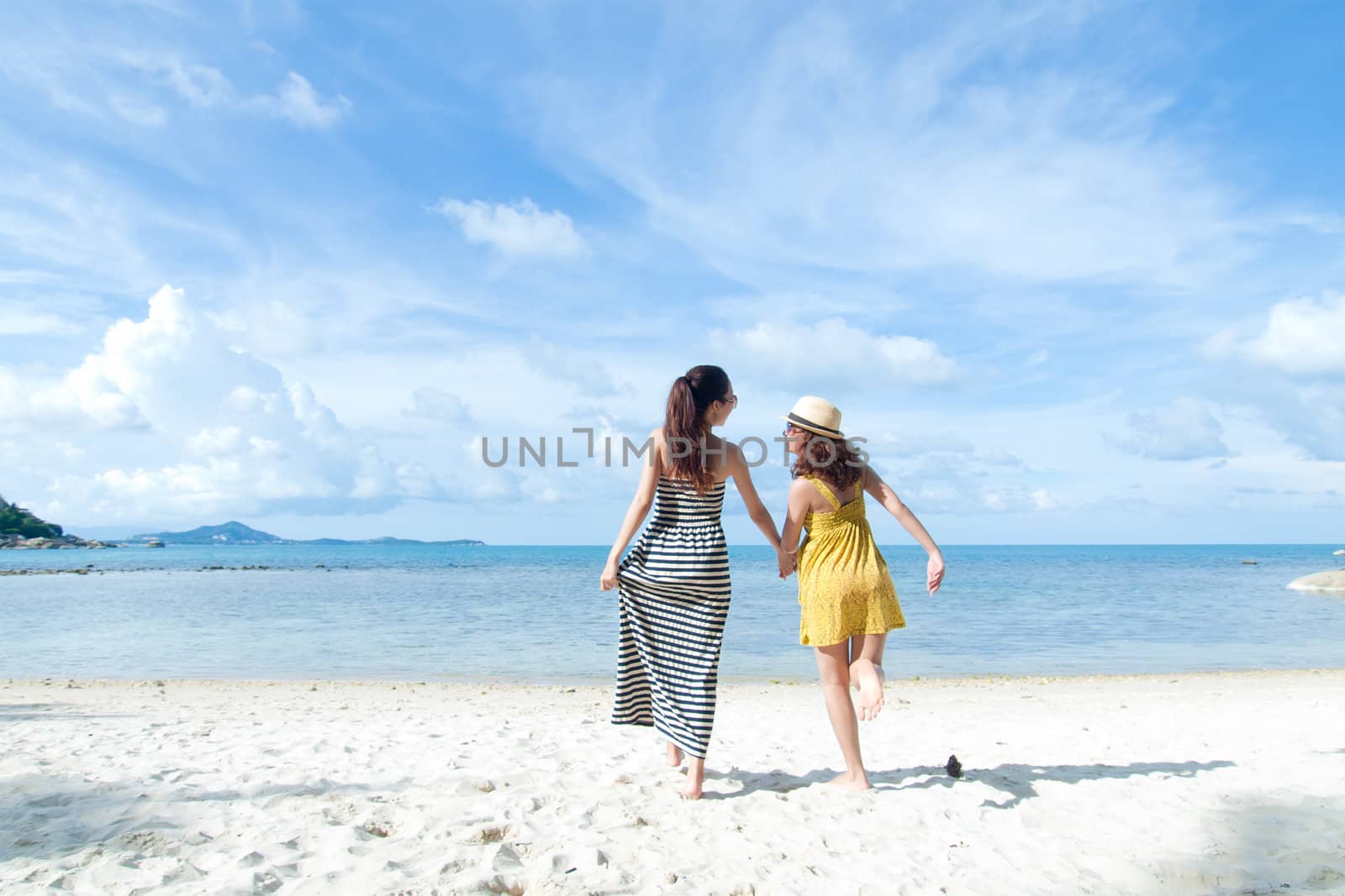 woman happy together on sand beach with blue sky background by jakgree