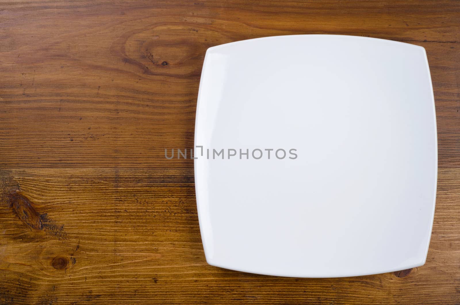 Empty white plate on wooden table