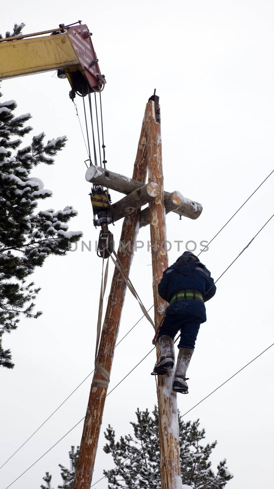 Electrician in blue overalls working at height