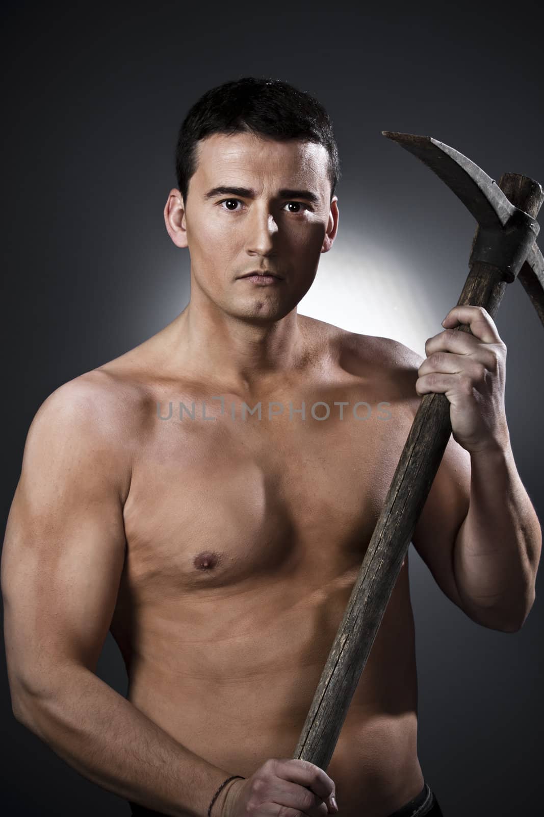 Young worker with pickaxe over black background