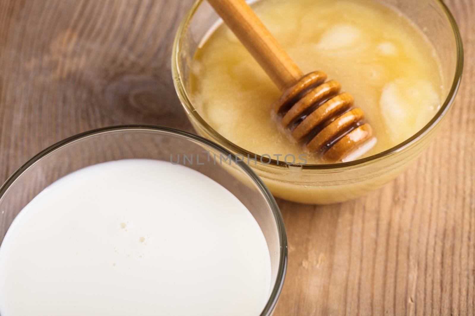 Milk and honey on the wooden table closeup