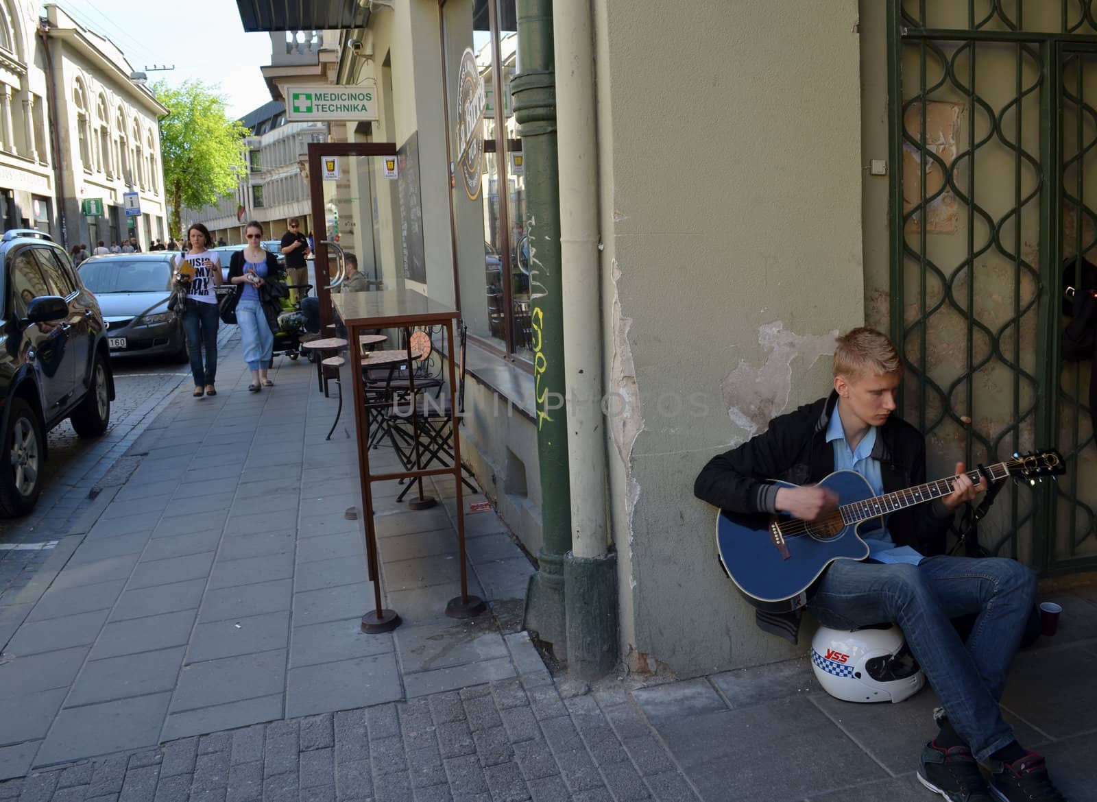 VILNIUS, LITHUANIA MAY 2012. Young man sit on motor bicycle helmet and play with guitar in street music day.