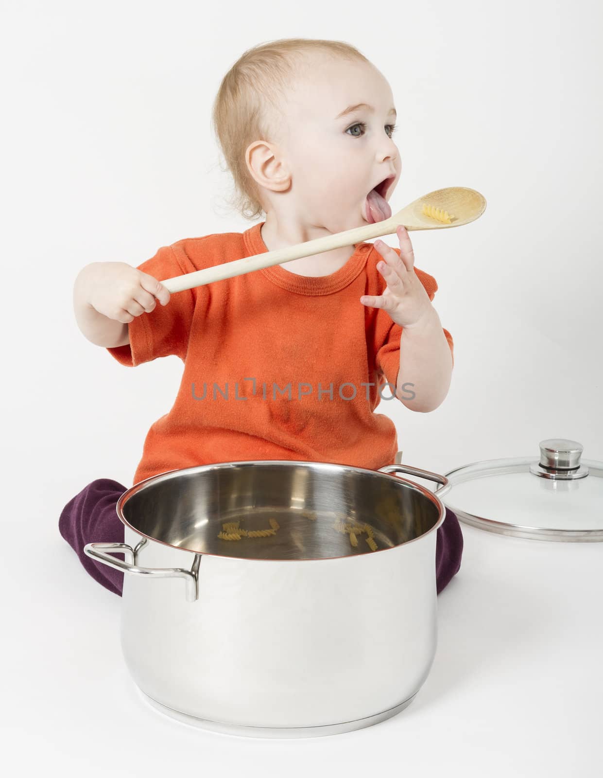 baby with big cooking pot and wooden spoon on neutral grey background