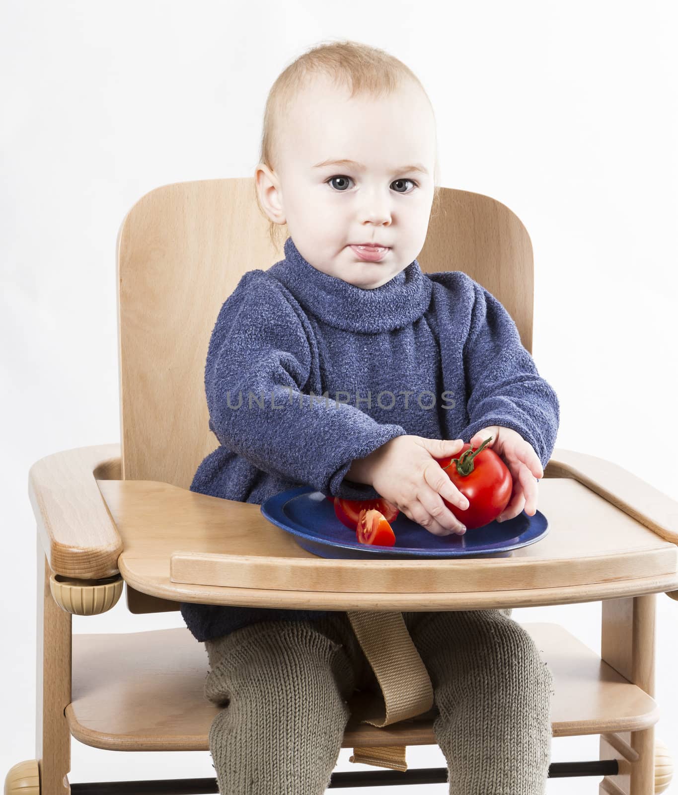 young child eating in high chair. neutral grey background