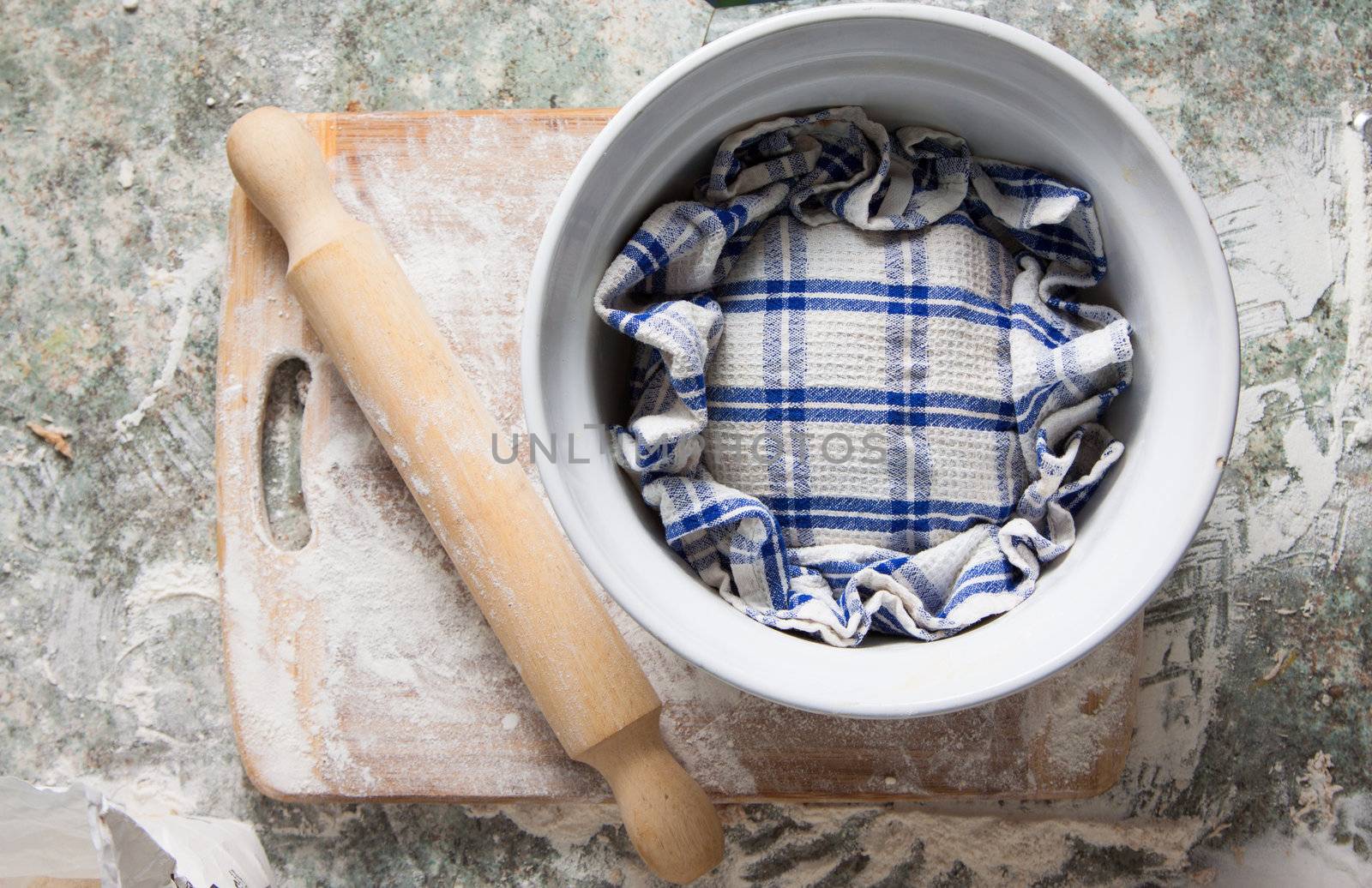 A homebaked dough is rising under a kitchen towel