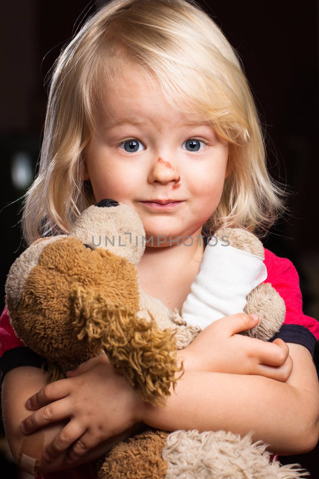 A injured cute little boy hugging his stuffed toy dog.