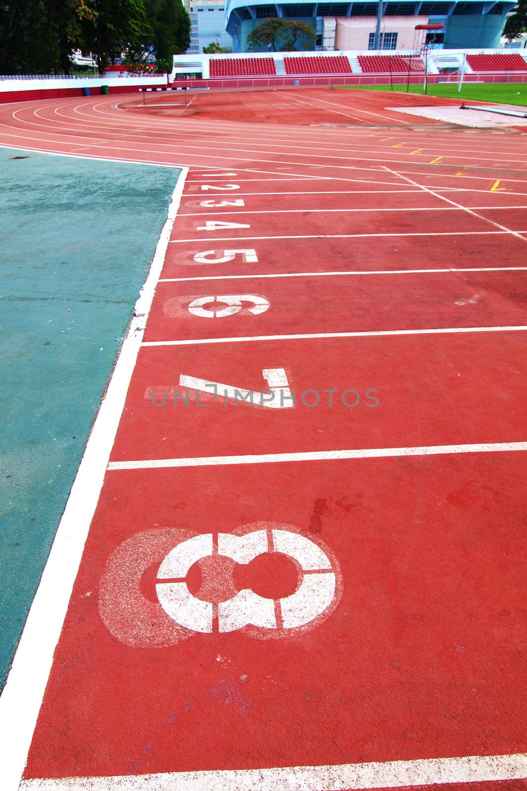 Lanes of a red race track with numbers and red seats in the stad by jakgree