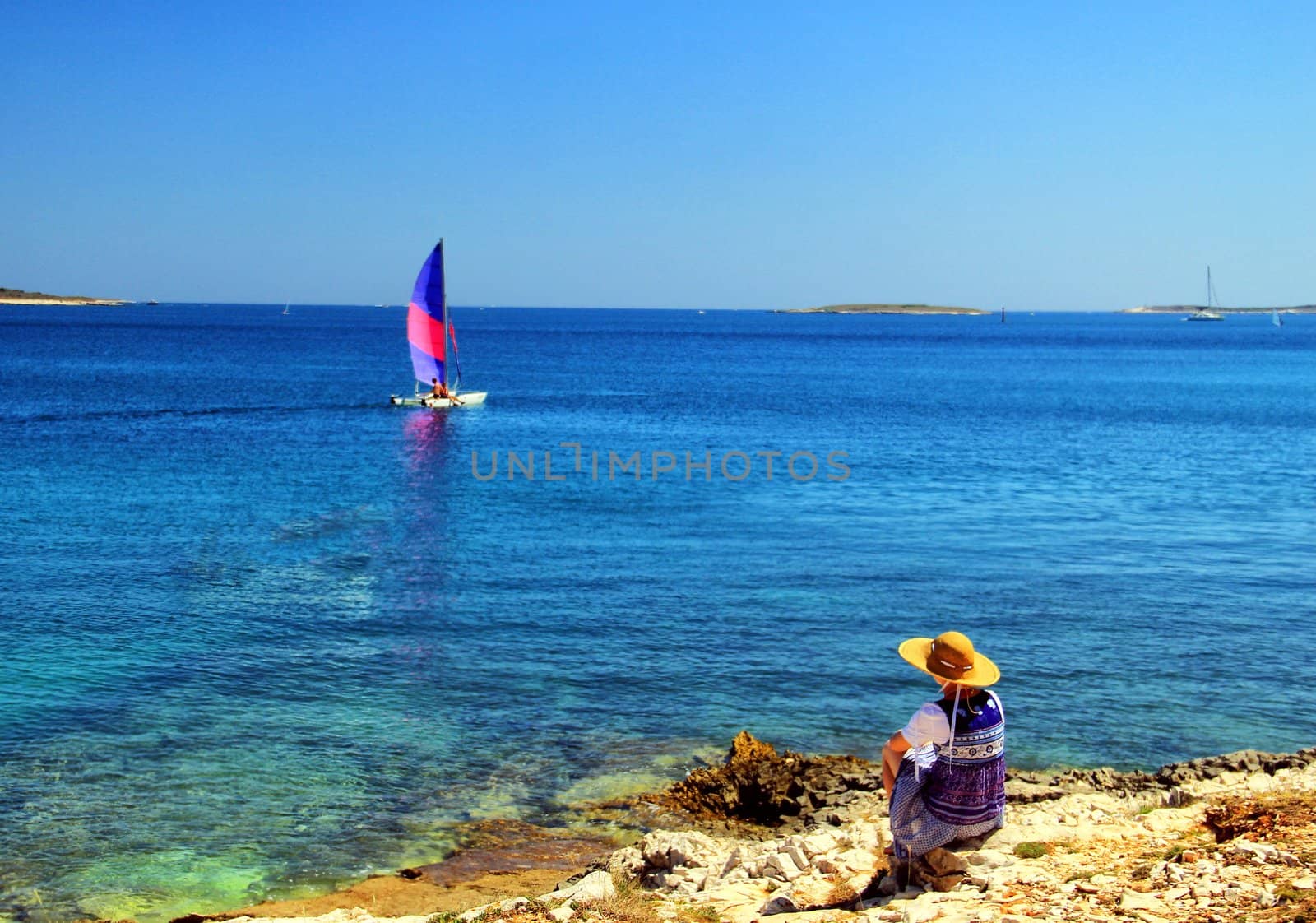 Young woman observing small sailing ship.