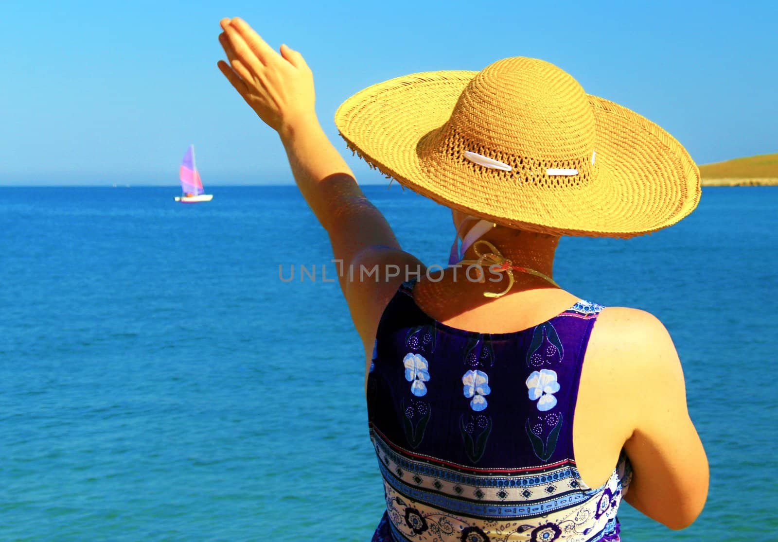 Young woman waving toward small boat.