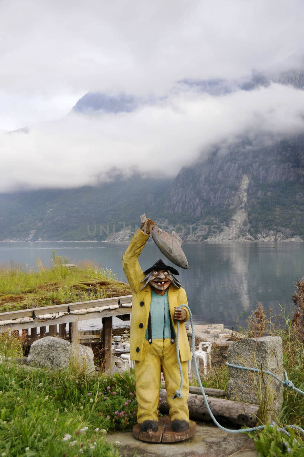 a wooden sculpture of fisherman is in camping of the quiet Norwegian bay
