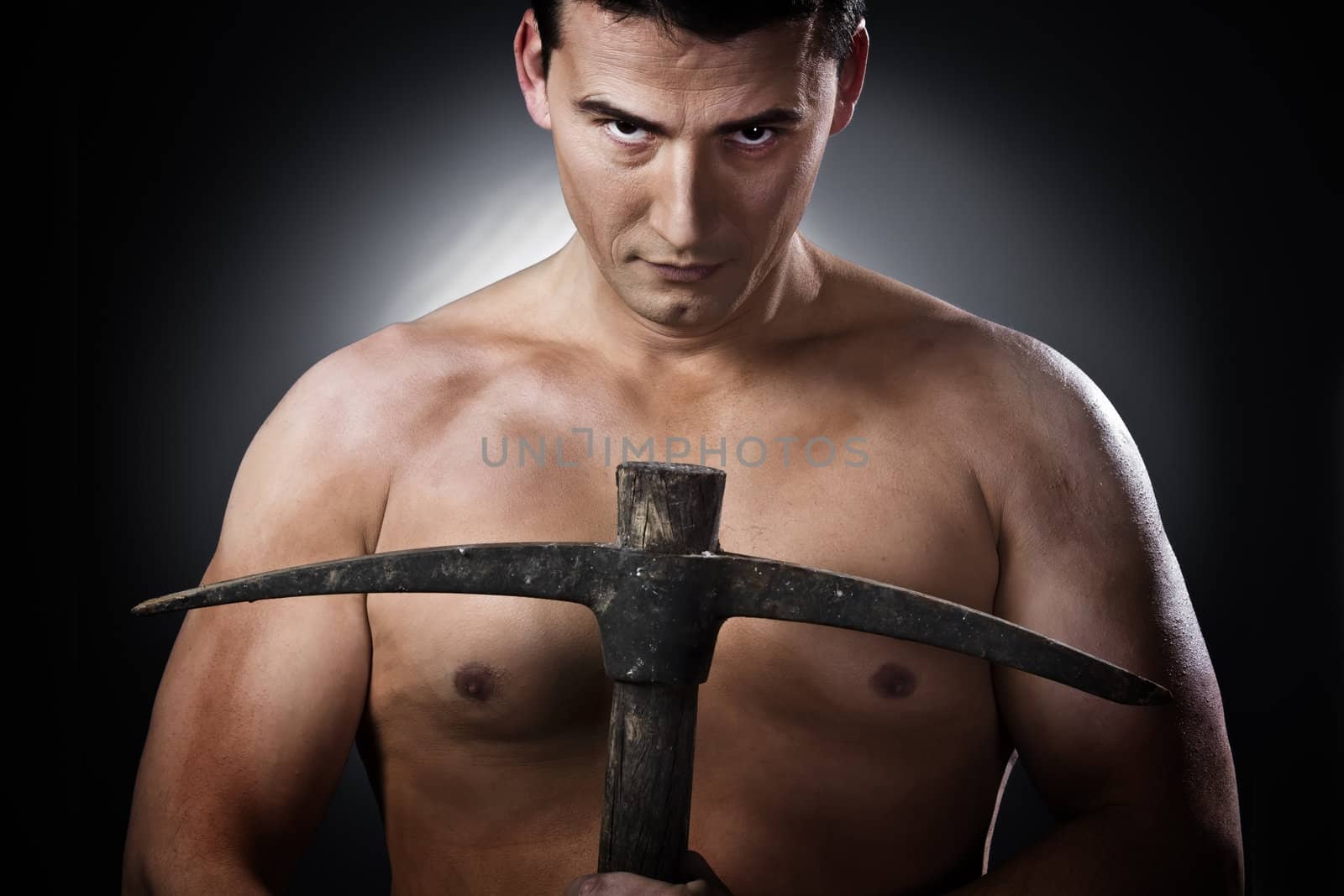 Topless construction worker with pick axe over grey background