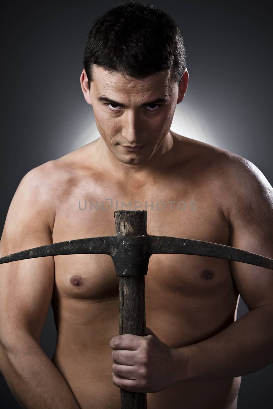 Topless construction worker with pick axe over grey background