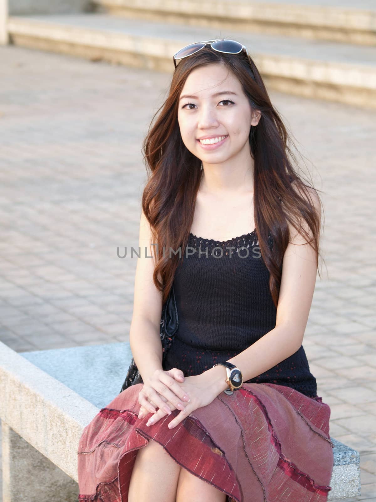 a portrait of attractive asian woman sitting on the bench in park