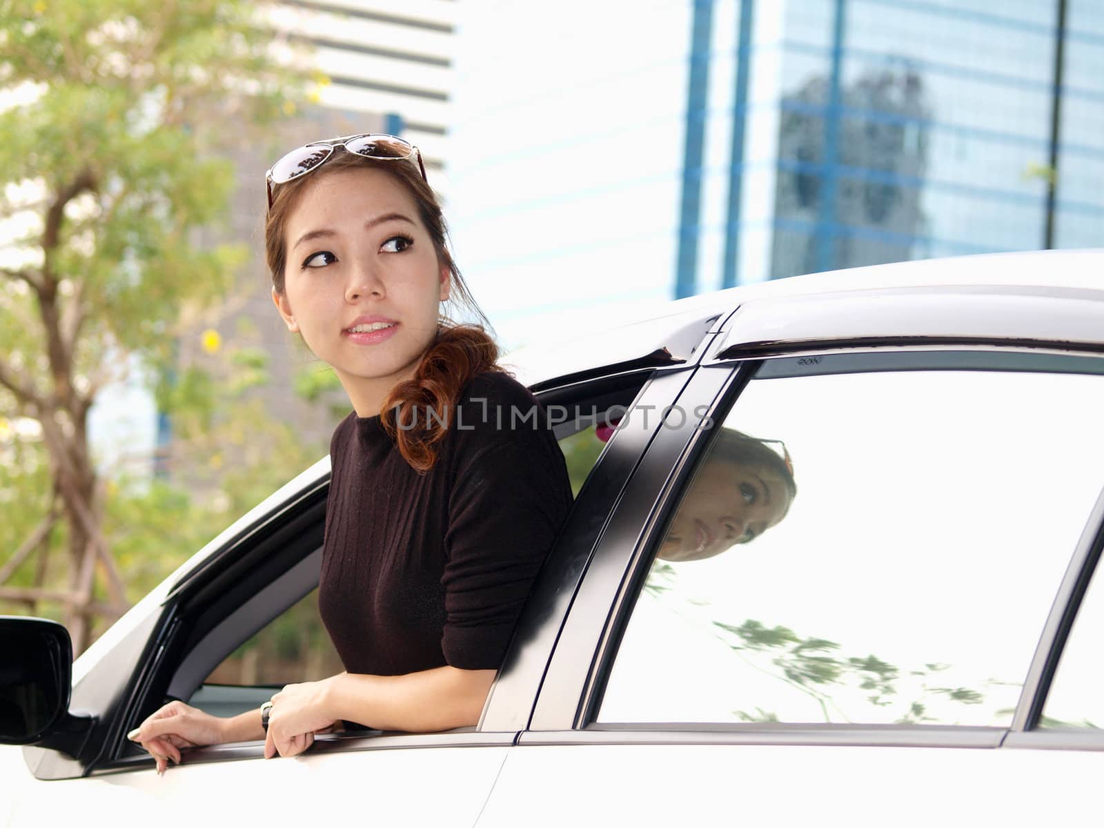 Young pretty Asian girl looking at back of car by jakgree