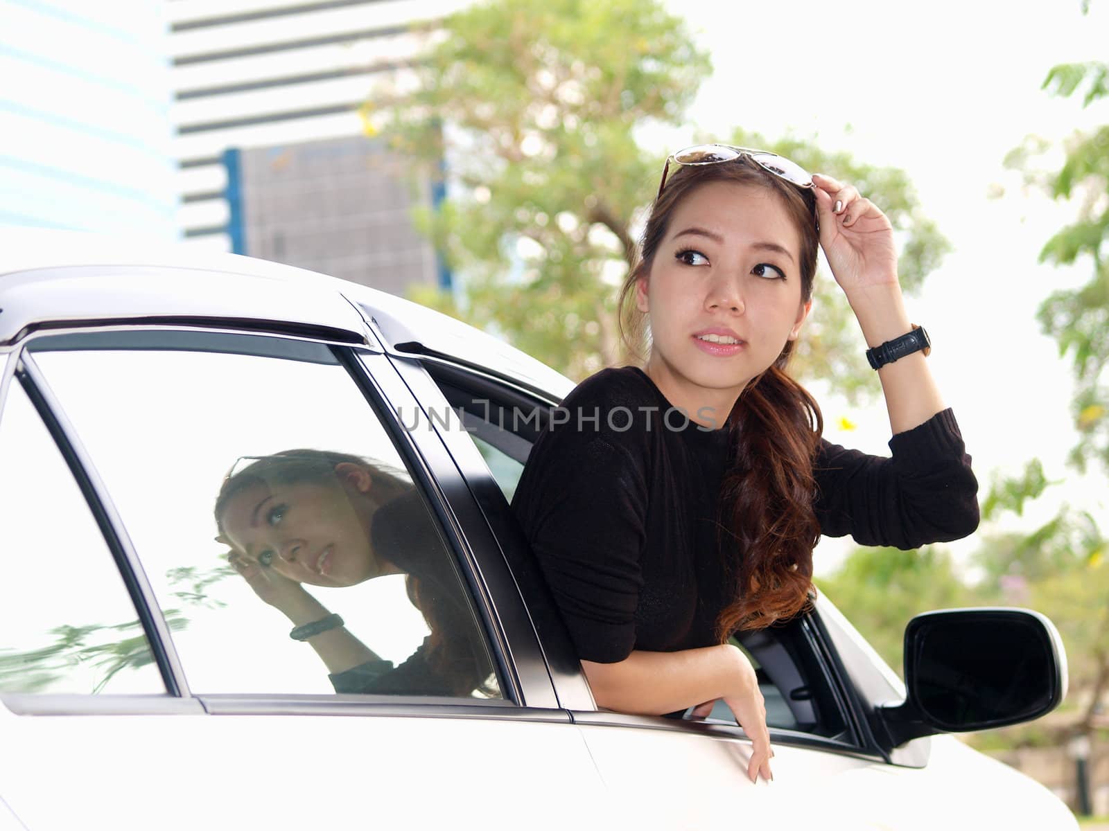 Young pretty Asian girl looking at back of car
