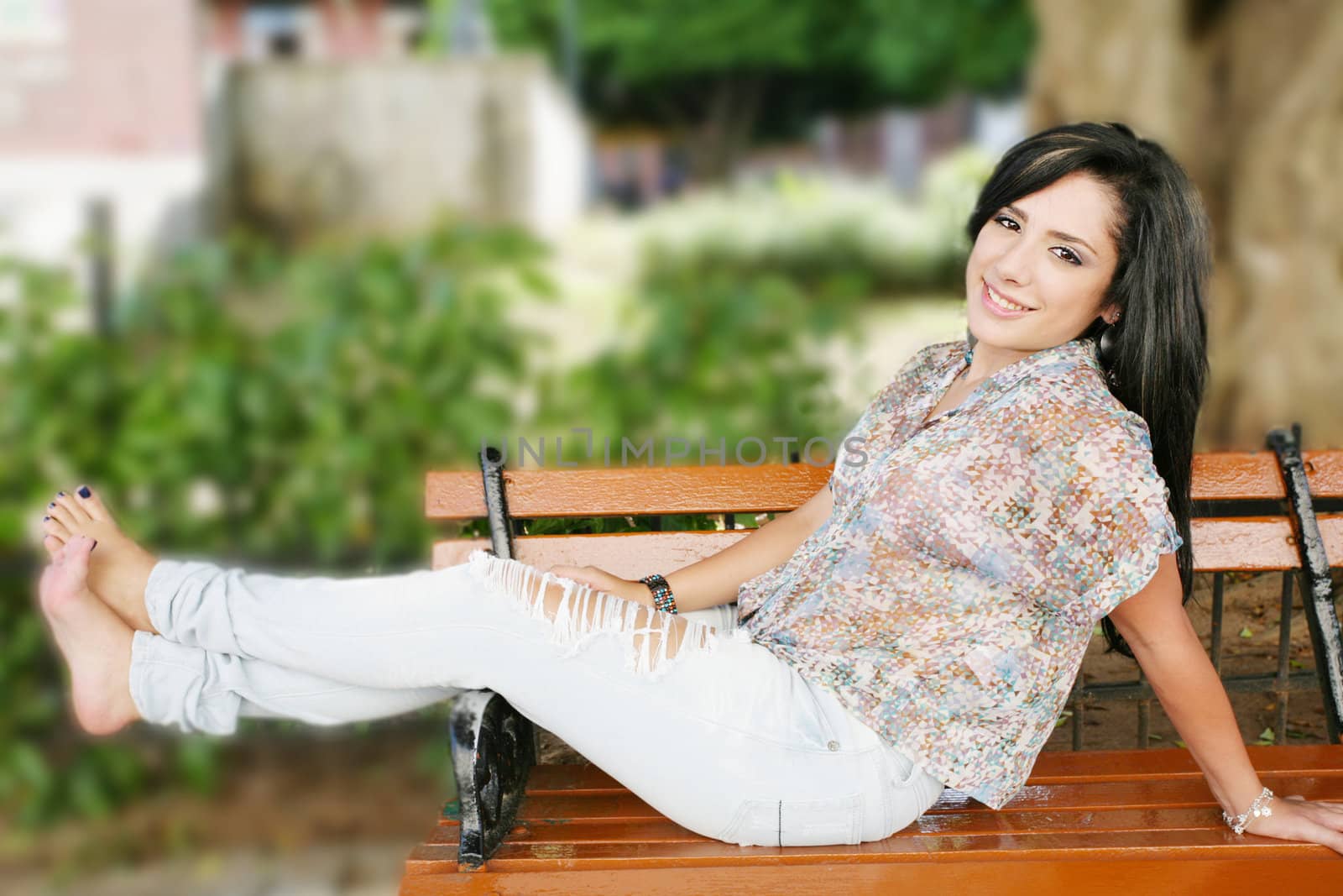 Portrait of smiling young girl sitting in bank in park by dacasdo