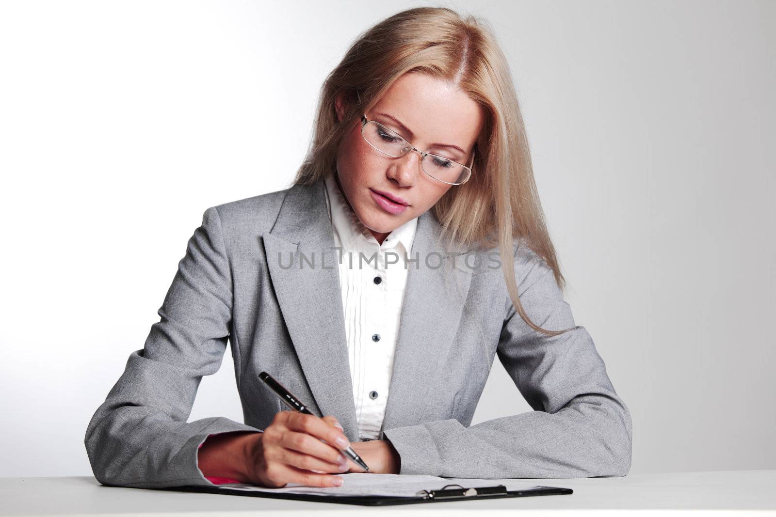 business woman writing in notebook on a gray background