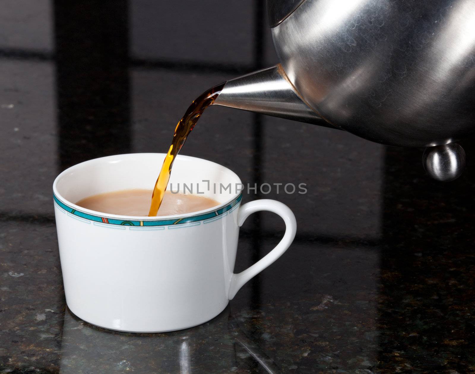 Fresh tea being poured into white cup on marble kitchen worktop