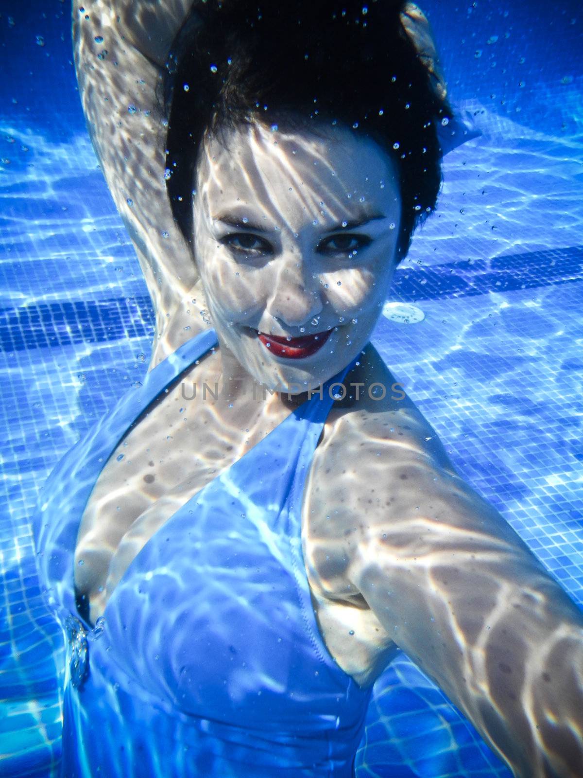 Vintage girl swimming and smiling underwater in a swimming pool