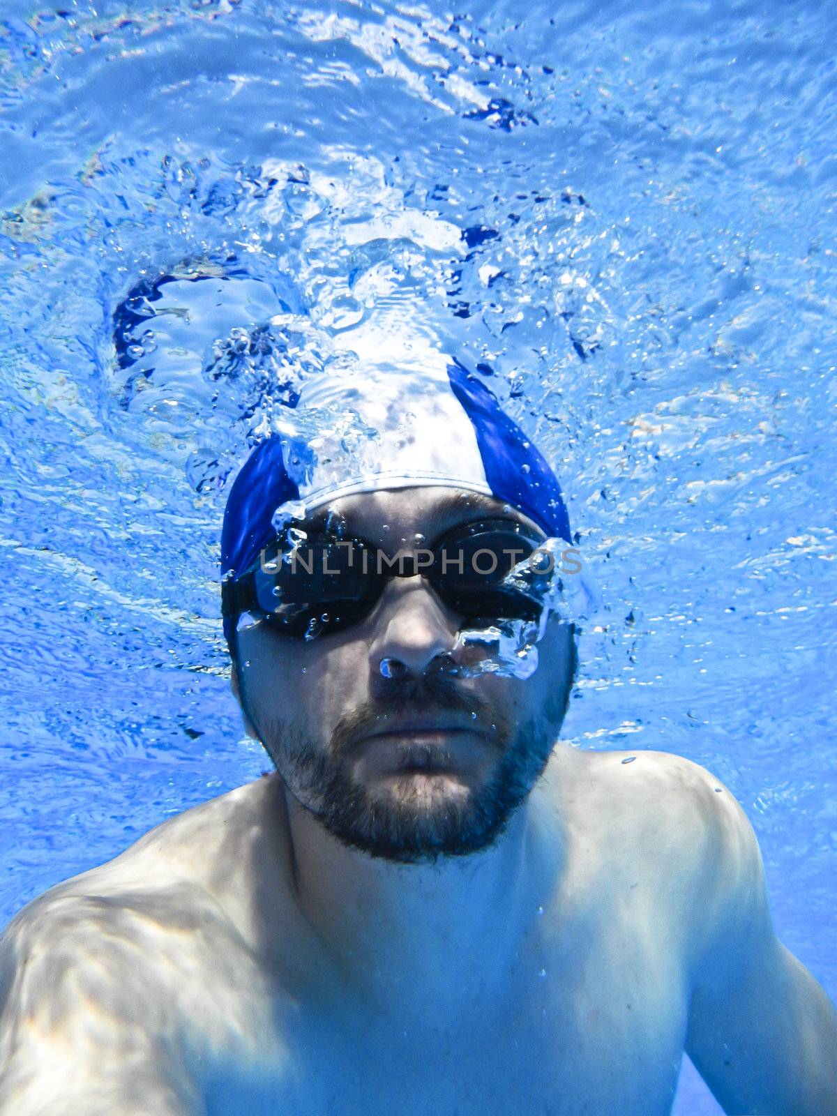 Man swimming with glasses underwater in pool