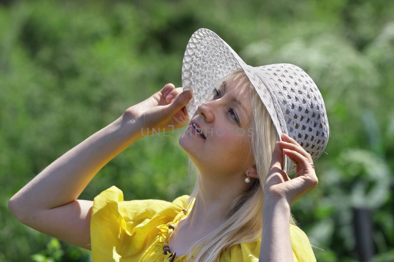 Woman looking up while holding his hat

