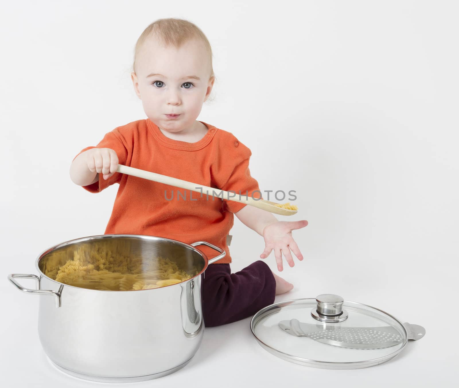 baby with big cooking pot and wooden spoon in neutral grey background