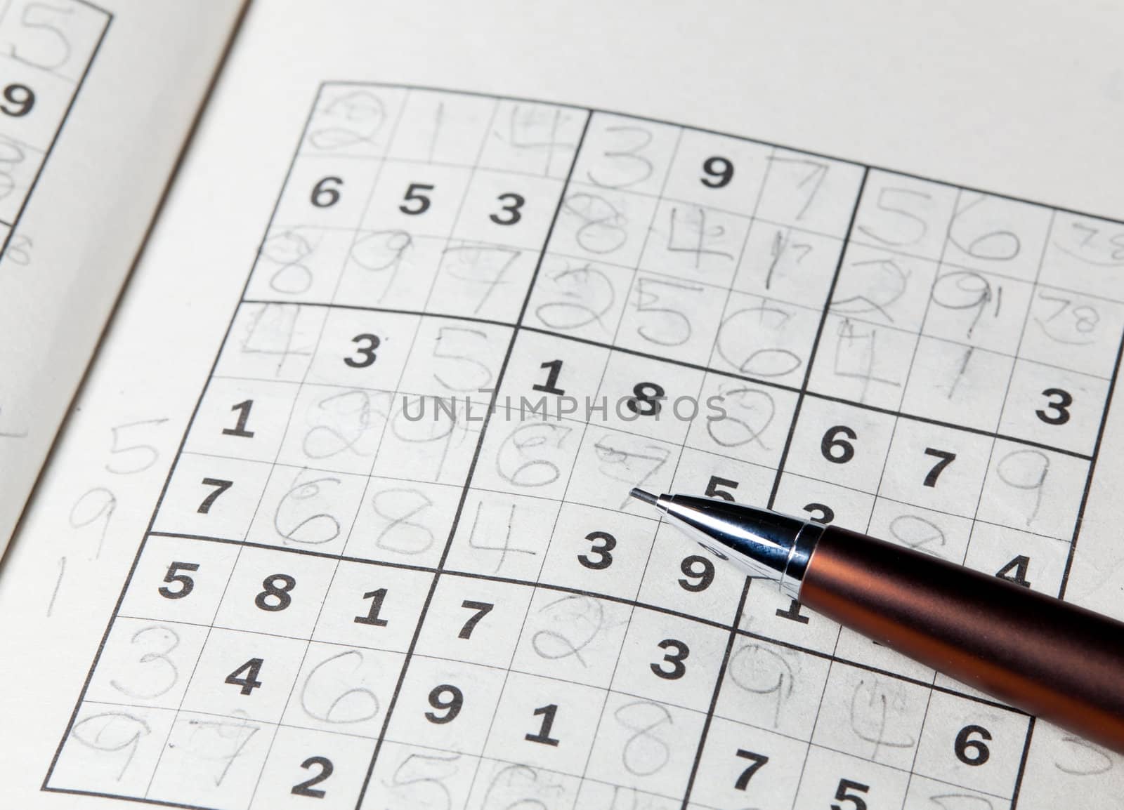 Pencil or pen resting on completed sudoku puzzle in book