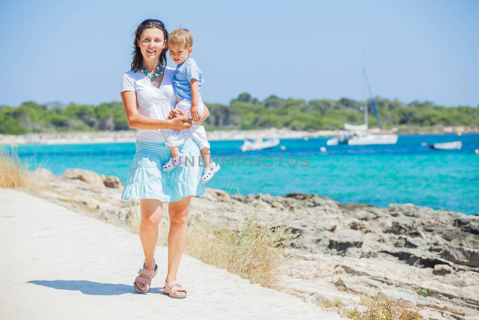 Young beautiful woman wis her son walking along tropical beach