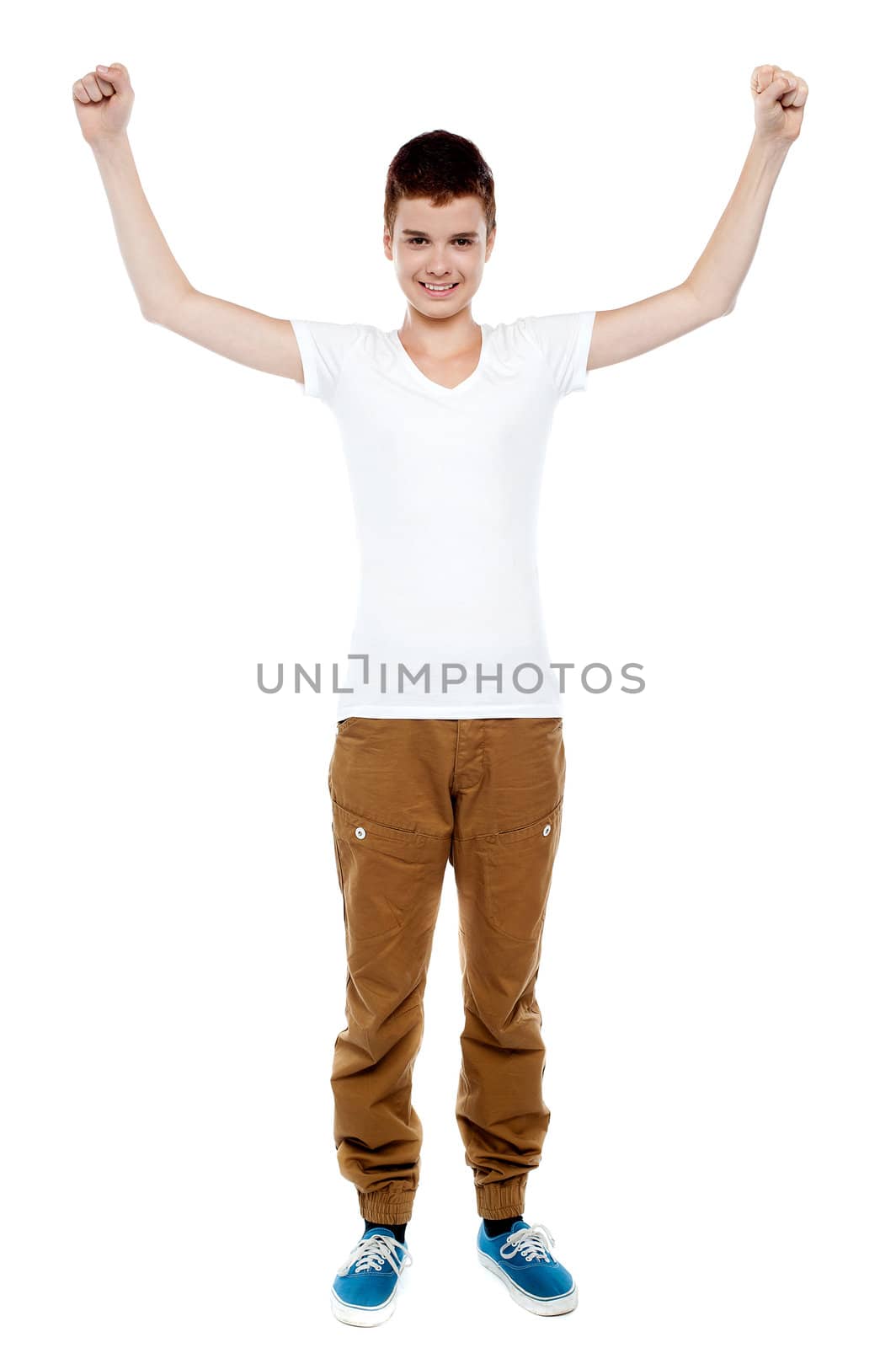 Cheerful young boy celebrating success posing with arms up