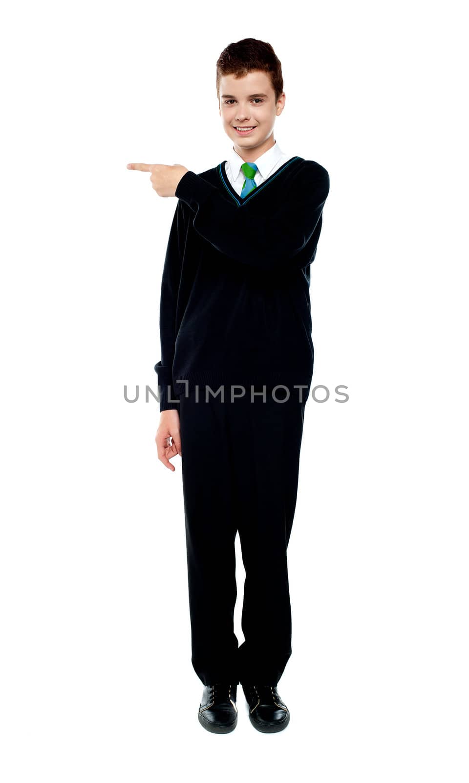 Full length portrait of attractive school boy pointing towards copy space area