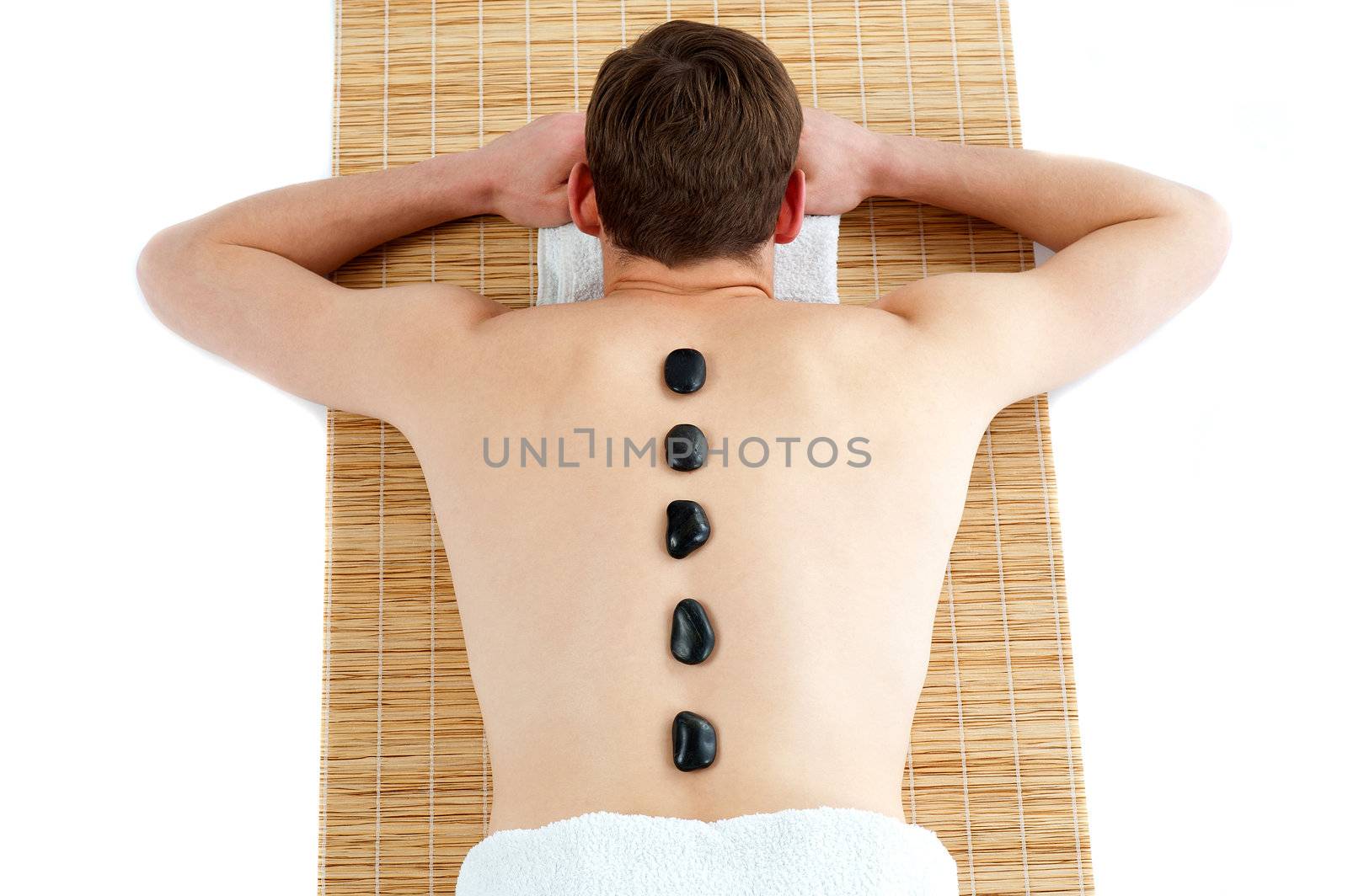 Man receiving hot stone therapy massage. Rear view portrait