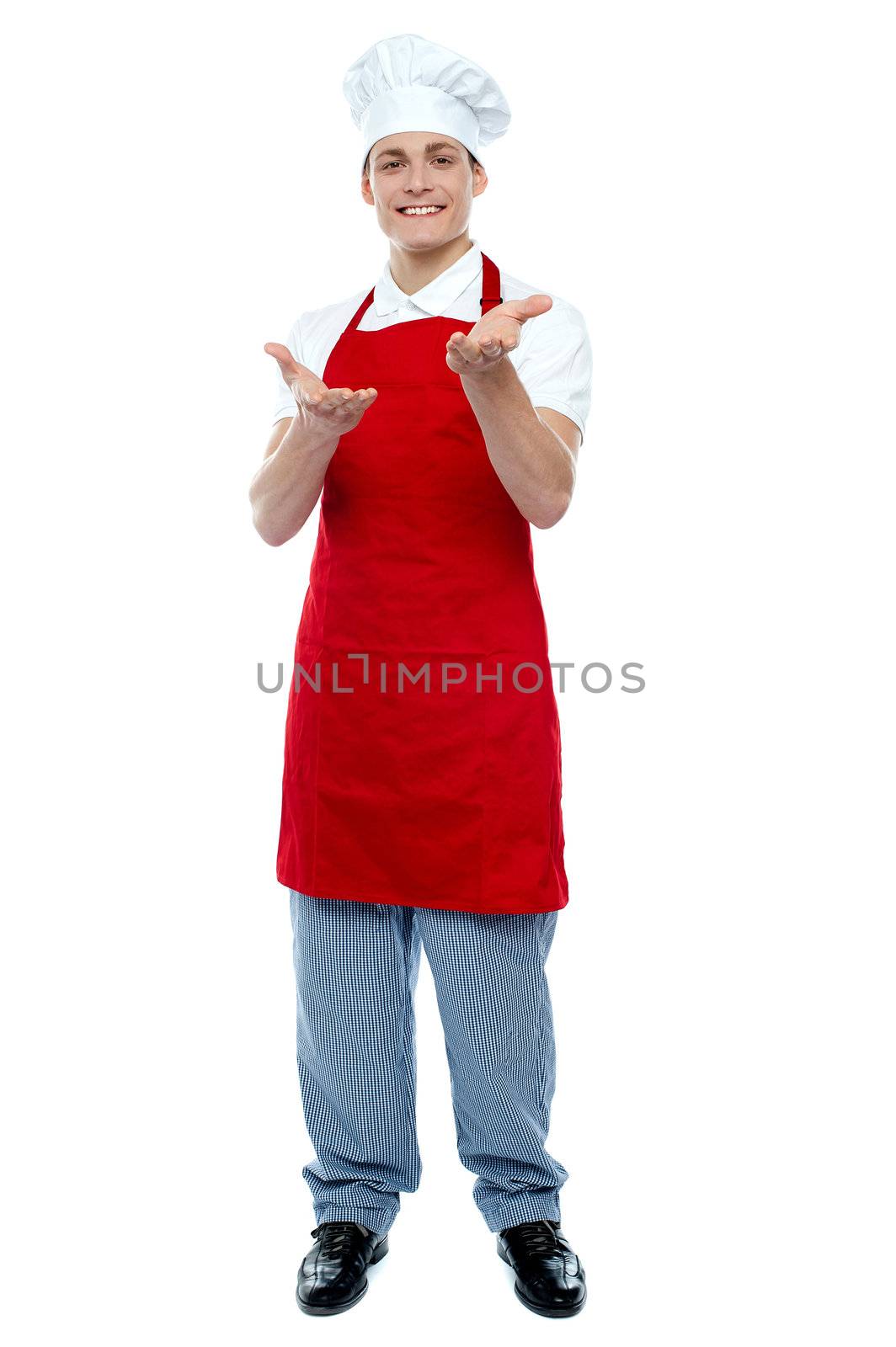 Full length portrait of handsome male cook welcoming you. At your service