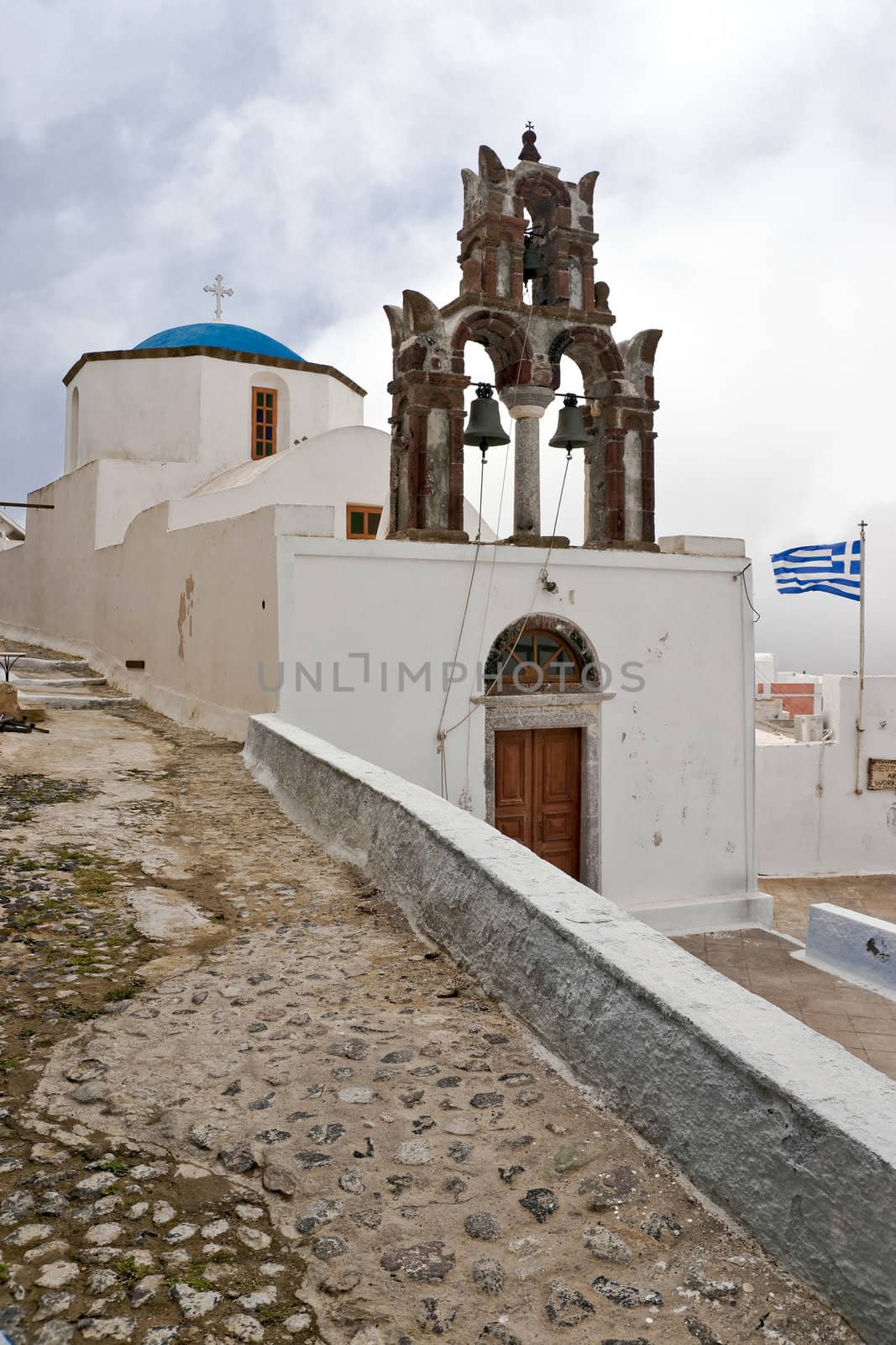 Old Greek church with belltower and greek flag