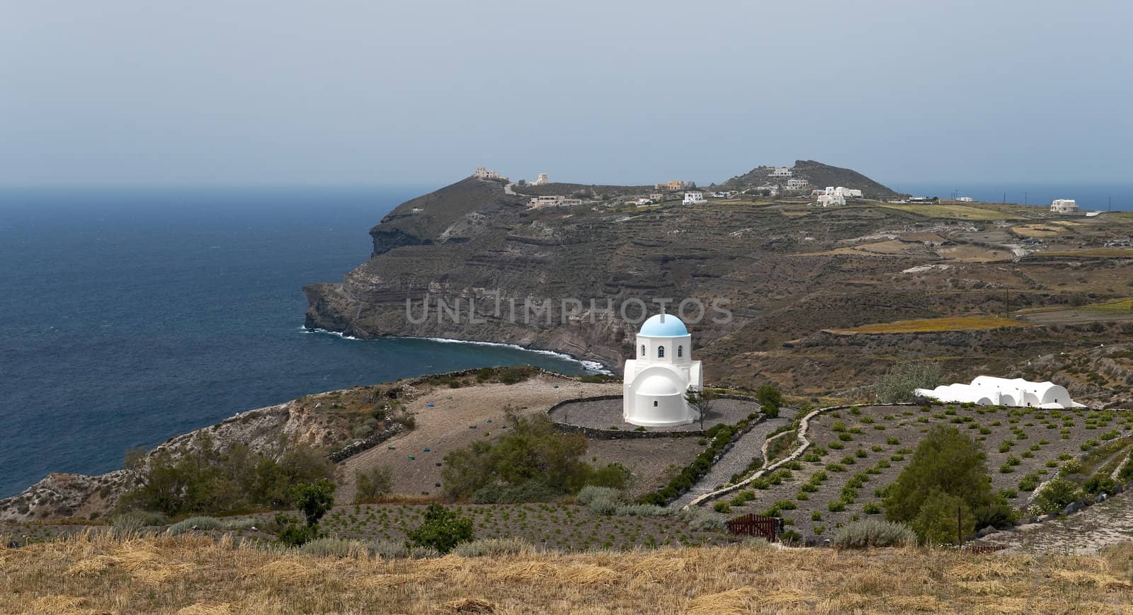 Lonely white church with blue cupola next to the sea