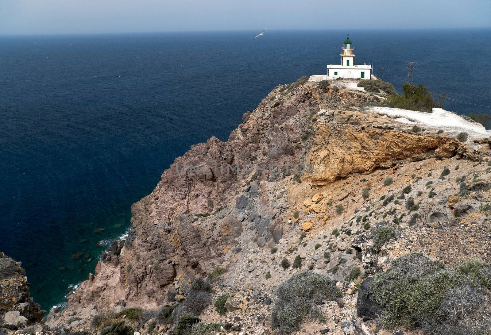 Santorini lighthouse on the rock with flying seagull 