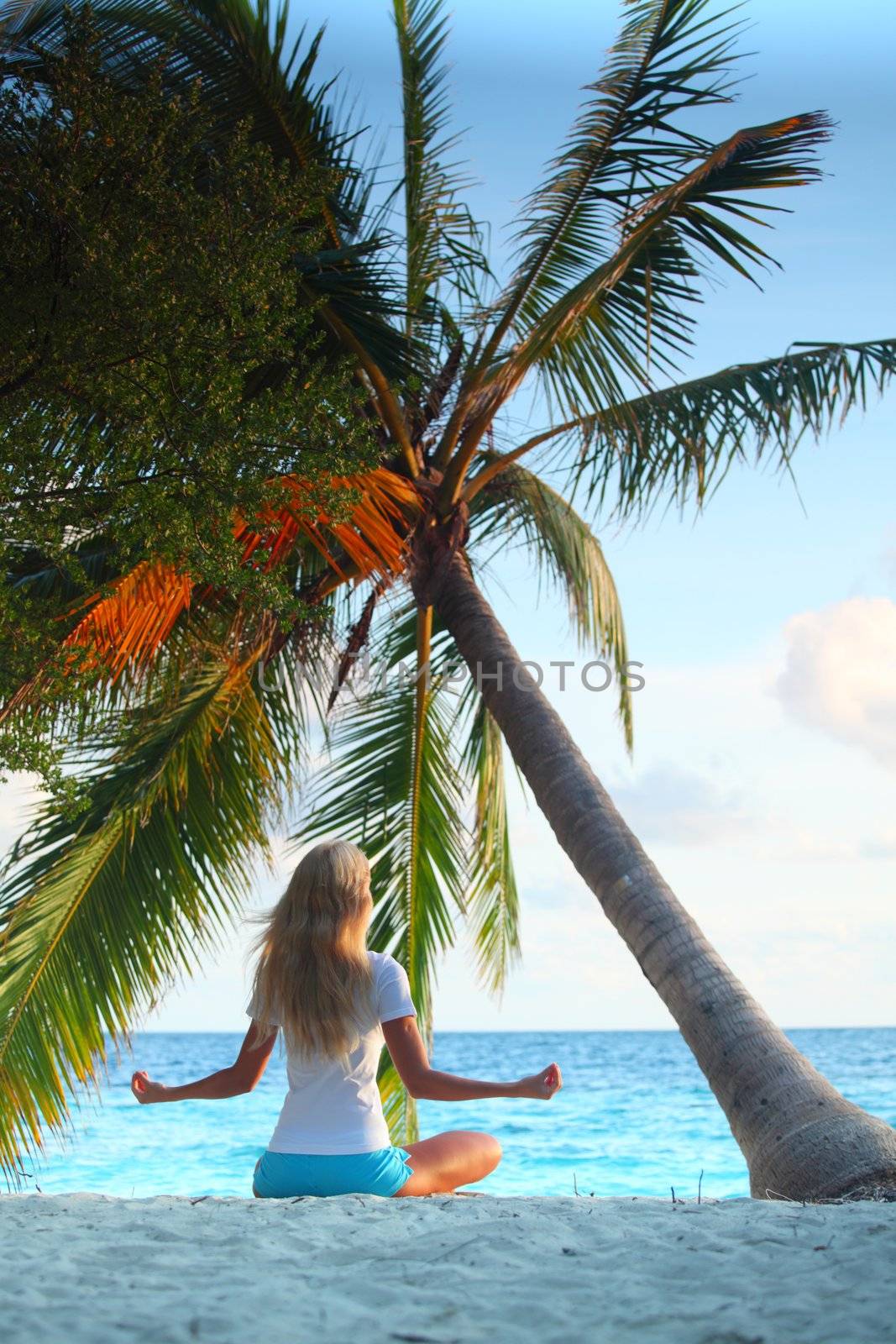 yoga woman on sea coast under palm