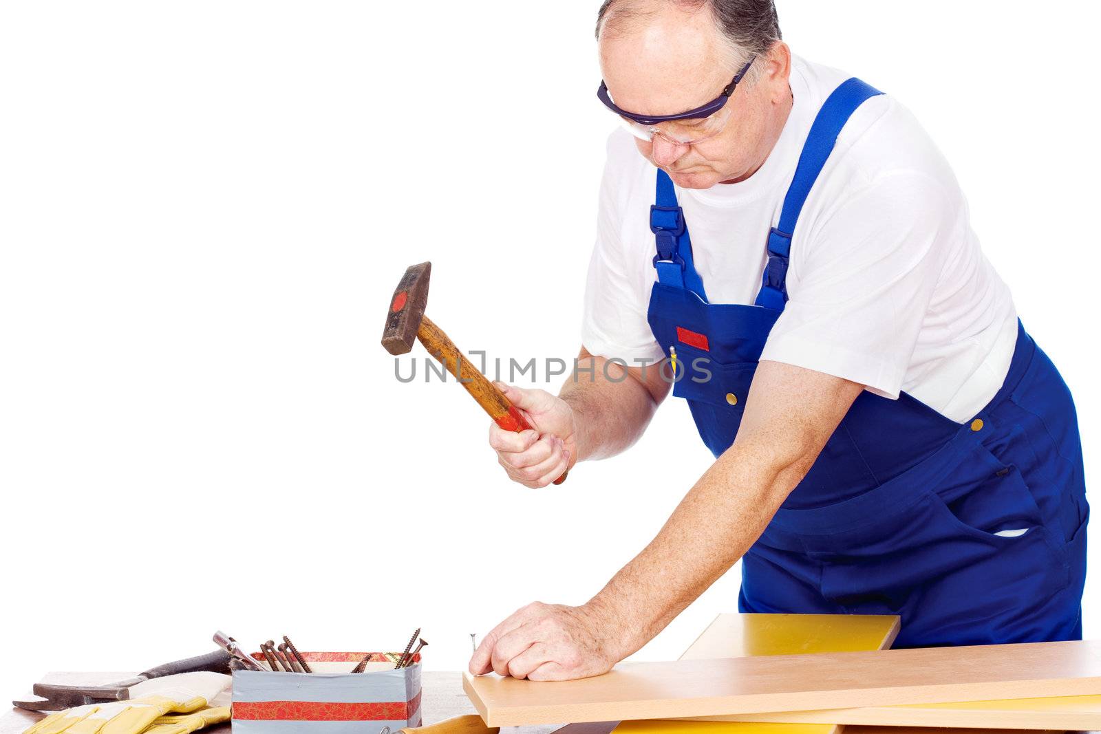 Middle age worker knocking the nail in board, isolated on white background