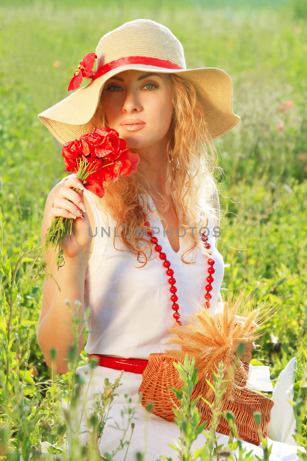 Woman in hat with poppy bouquet in meadow