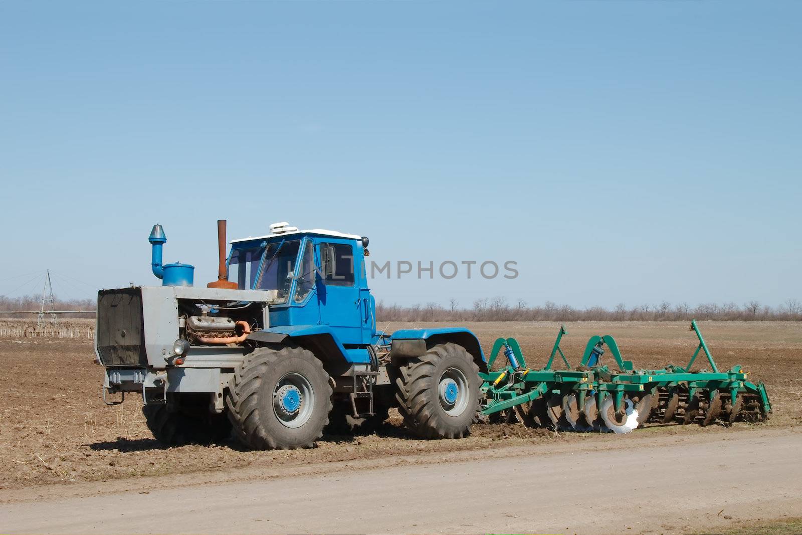 Blue tractor with a plow in a field