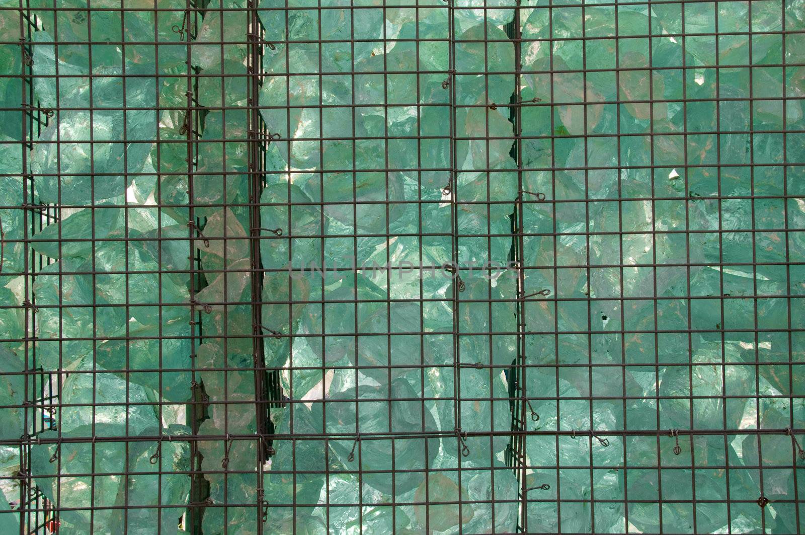 A pile of decorative pieces of glass, enclosed in a metal grate.