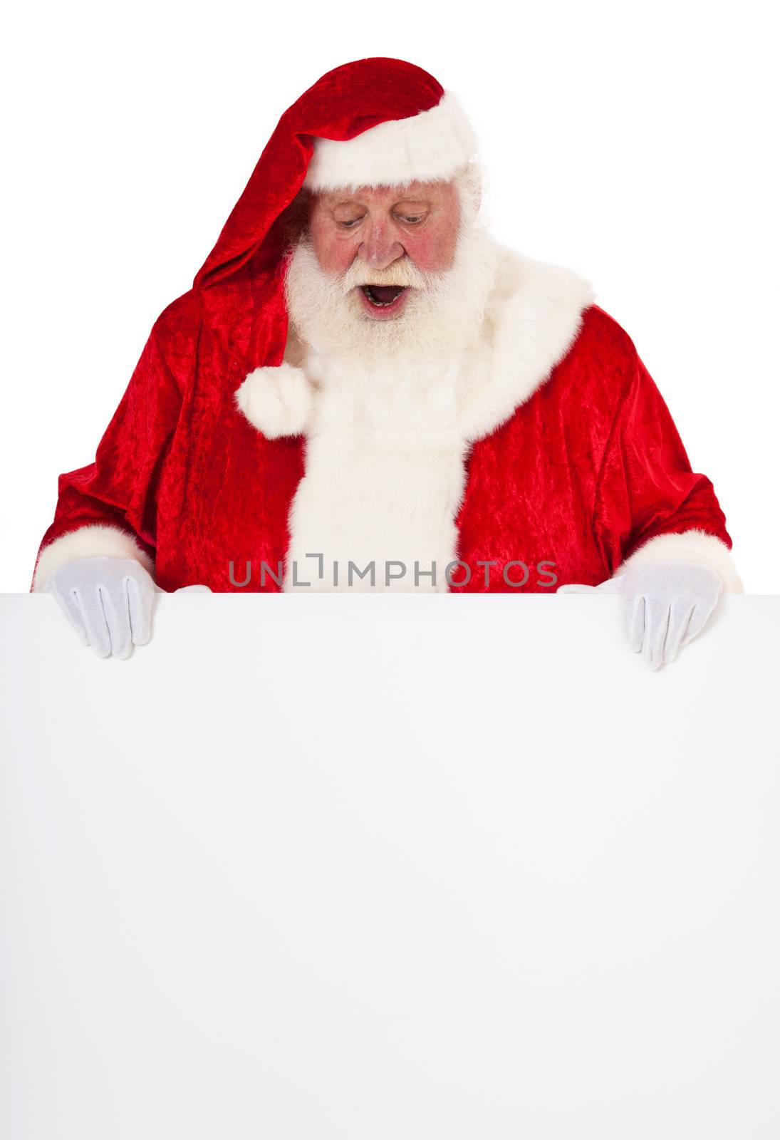 Santa Claus in authentic look behind blank sign with surprised expression. All on white background.